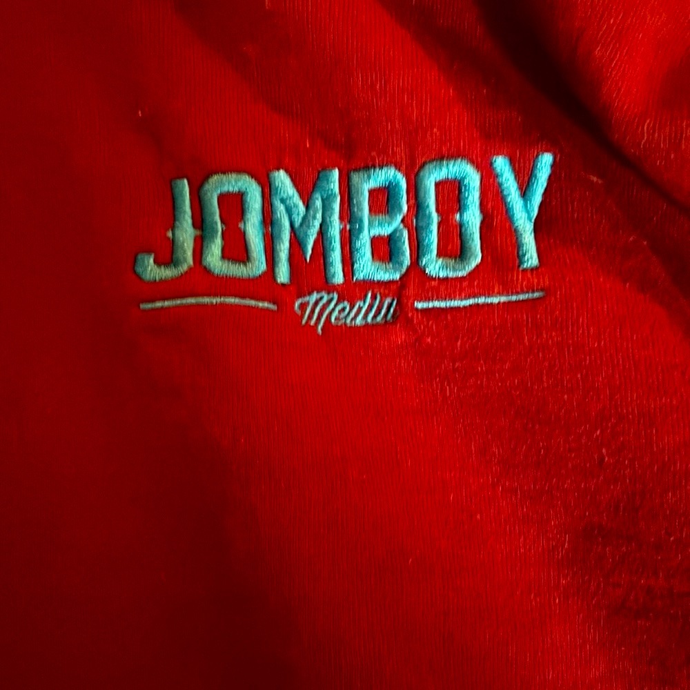 Burgundy pullover hoodie sweatshirt with "Jomboy Media" embroidered in blue